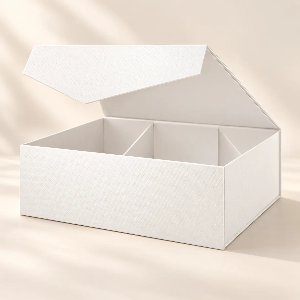 The gift box, open and empty: a white textured box with its lid raised and inner dividers.
